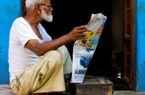 An elderly man reading a newspaper