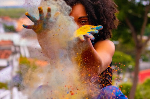 A woman throwing a cloud of multi-coloured particles