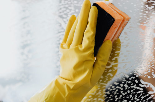 A hand holding a sponge cleaning a mirror