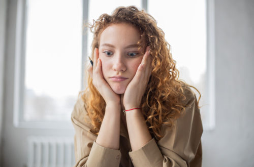 A woman holding her head looking puzzled