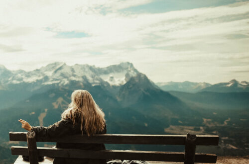 A woman on a hillside looking into a mountainscape