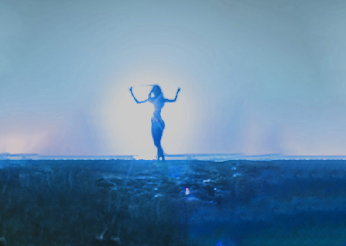 A blue toned image of a woman dancing in the sunlight