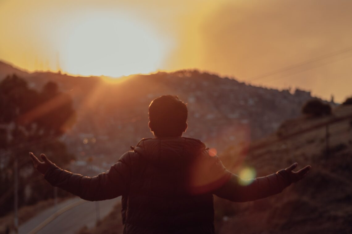 A man paying homage to the sun. the city and the fields below.