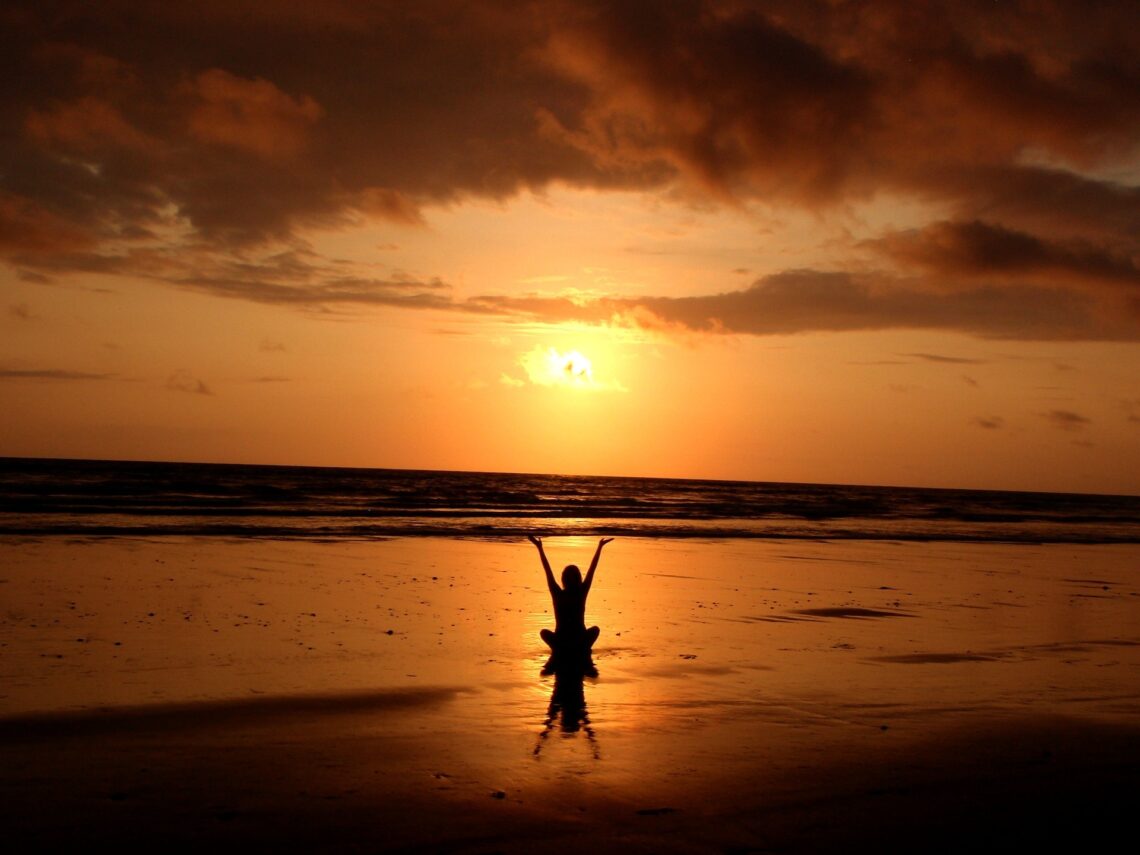 A woman performing the setting of the sun ritual on a beach