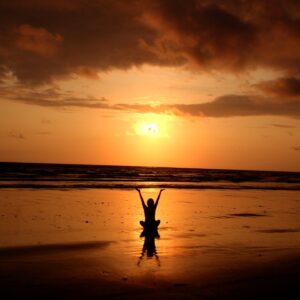 A woman performing the setting of the sun ritual on a beach