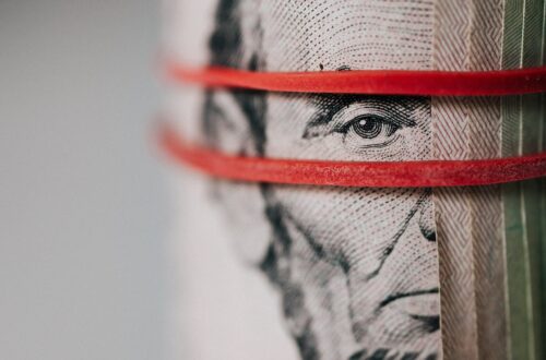 A furled banknote showing Abe Lincoln peeping through two red rubber bands.