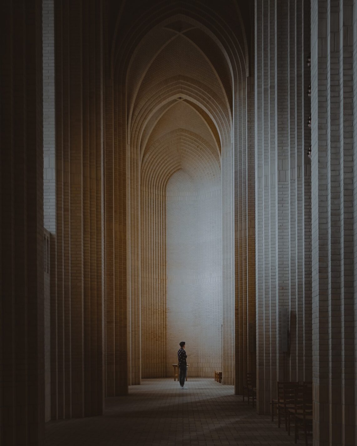 A person situated within a tall and narrow theological archway.