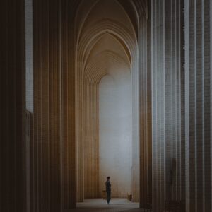 A person situated within a tall and narrow theological archway.