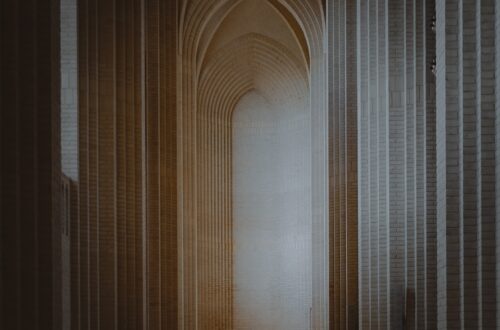 A person situated within a tall and narrow theological archway.