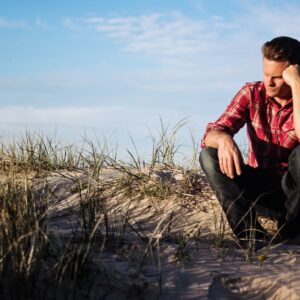 A man sitting at a cliff's edge and looking confused