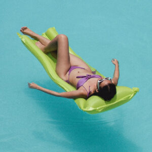 A person relaxing on an air mattress in a blue pool.