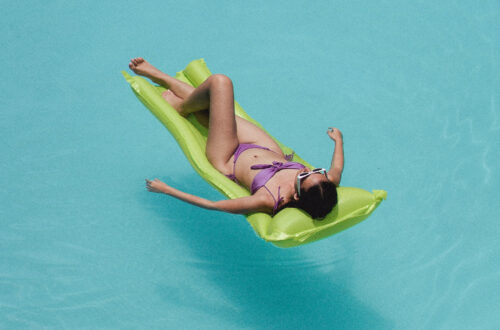 A person relaxing on an air mattress in a blue pool.