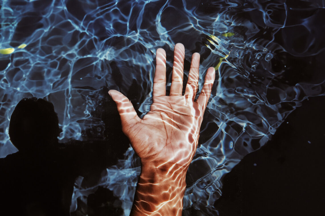 A hand just below the surface with a ghost like image in the background.
