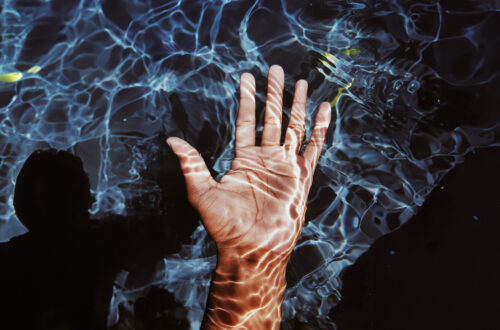 A hand just below the surface with a ghost like image in the background.