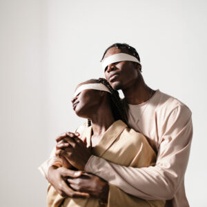 A blindfolded couple hugging.